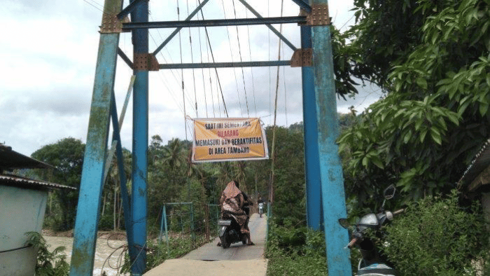 Spanduk pelarangan sementara aktivitas penambangan di jembatan menuju area penambangan Desa Tulabolo, Kecamatan Suwawa Timur, Kabupaten Bone Bolango, Provinsi Gorontalo Sabtu (13/7/2024). Foto: msn.com/ tribungorontalo